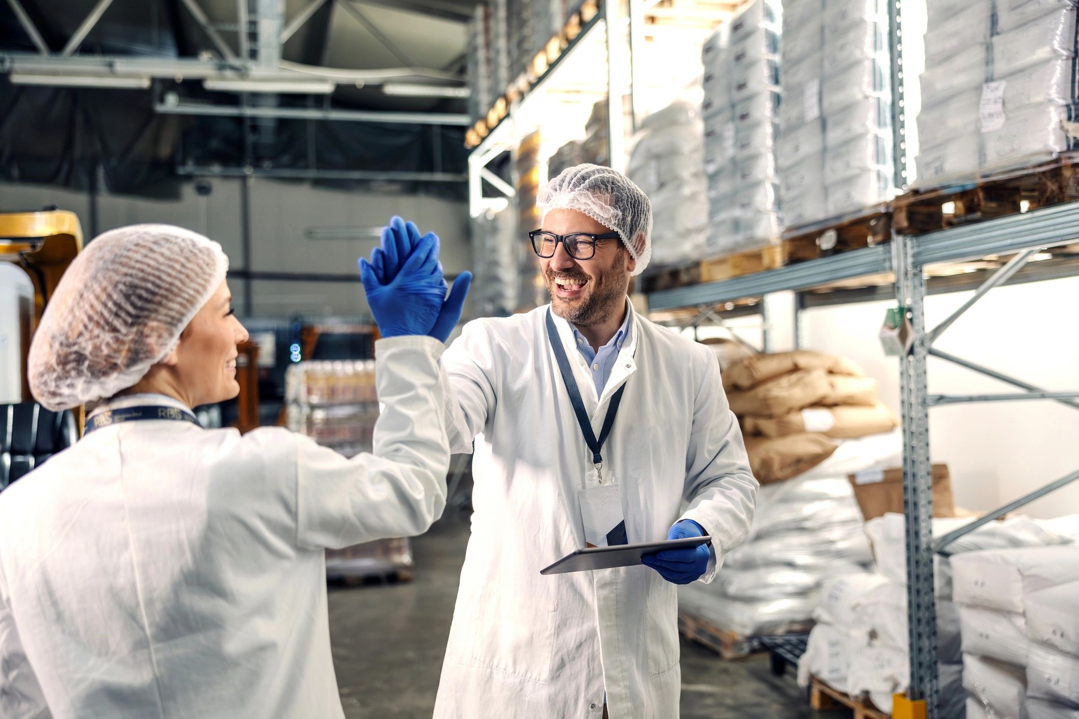 Food factory workers high fiving celebrating success